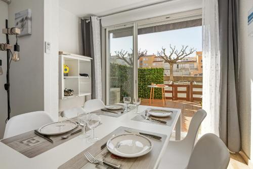 une salle à manger blanche avec une table blanche et des chaises blanches dans l'établissement Cap City - Studio climatisé à Agde, au Cap d'Agde