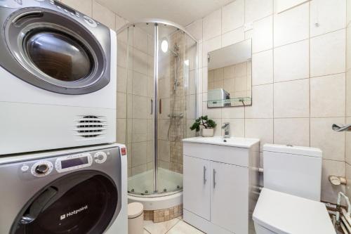 a bathroom with a washing machine and a shower at The Archway Collection in London