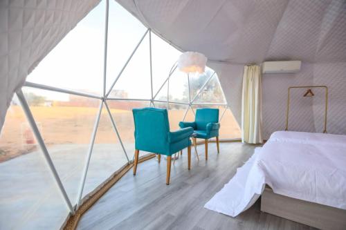 a bedroom with two chairs and a bed in a tent at Ciel D'Etoile Sahara in Merzouga
