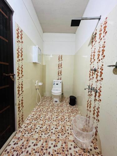 a bathroom with a toilet and a tiled floor at Eden cabana in Alleppey