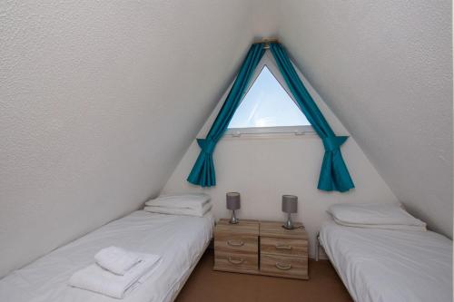 two beds in a attic room with a window at Chalet 137 in Deal