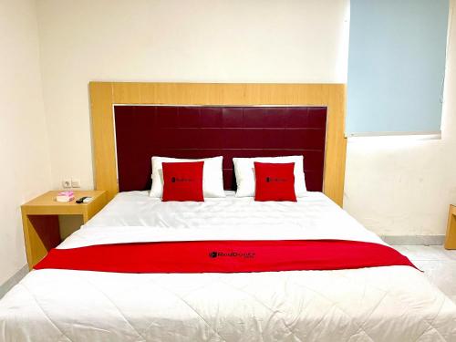 a bedroom with a large bed with red pillows at RedDoorz @ Wisma Graha Andi Djemma in Manda