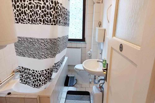La salle de bains est pourvue d'un rideau de douche noir et blanc. dans l'établissement Cozy Apartments in Büdingen, à Büdingen