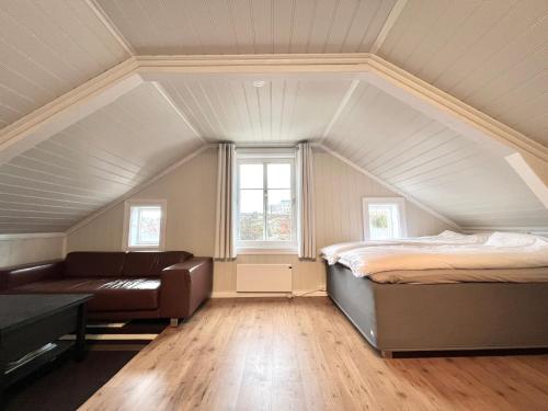 a attic bedroom with a bed and a couch at Sentrum - Koselig hus med parkering in Arendal