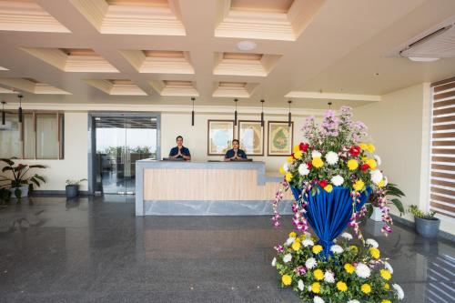 two people at a reception desk in a lobby with flowers at Regenta Central Puri Odisha in Puri