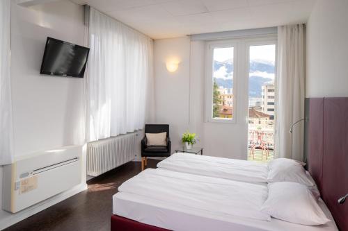 um quarto com uma cama branca e uma janela em Hotel Rio Muralto em Locarno