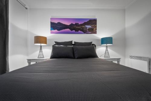 a bedroom with a large bed with two lamps at Hobart City Townhouse in Hobart