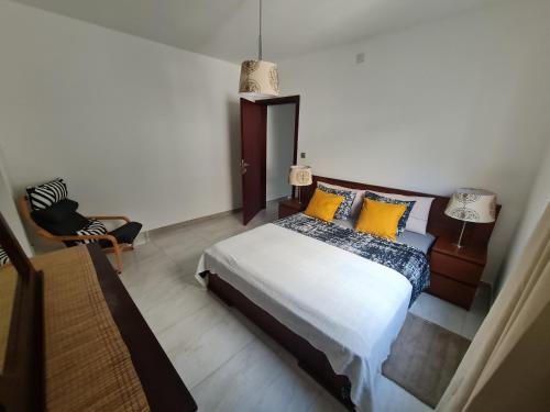 Un dormitorio con una cama con almohadas amarillas y una silla en Lovely 1-Bed Apartment in Luanda en Luanda