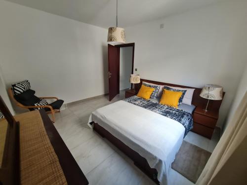 um quarto com uma cama com almofadas amarelas e uma cadeira em Lovely 1-Bed Apartment in Luanda em Luanda