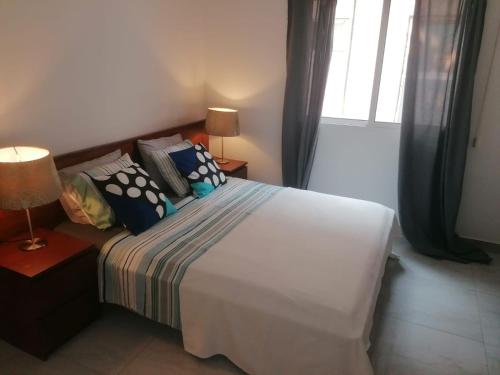 a bedroom with a white bed with pillows and a window at Lovely 1-Bed Apartment in Luanda in Luanda