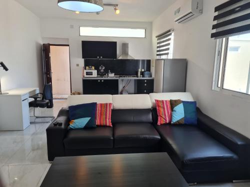 a living room with a black leather couch and a kitchen at Lovely 1-Bed Apartment in Luanda in Luanda