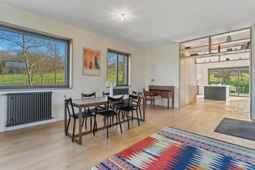 - un salon avec une table, des chaises et une grande fenêtre dans l'établissement Maison face à la mer dans un domaine écologique, à Villerville