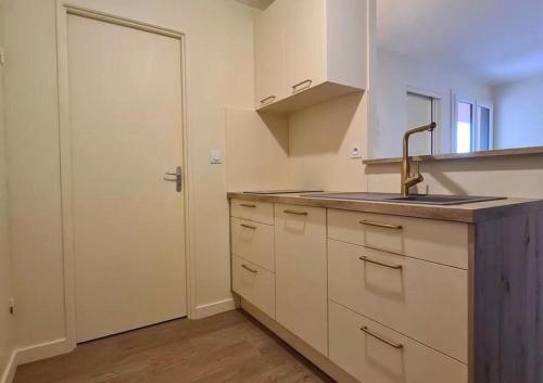 eine Küche mit weißen Schränken, einem Waschbecken und einer Tür in der Unterkunft La Perle Marine in Fleury
