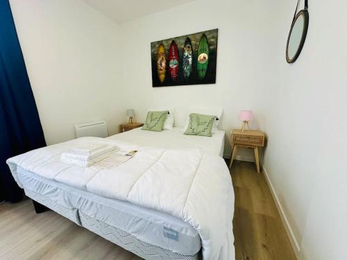 1 dormitorio con 1 cama con sábanas blancas y almohadas verdes en Charmant T2 * proche plage * parking gratuit en La Rochelle