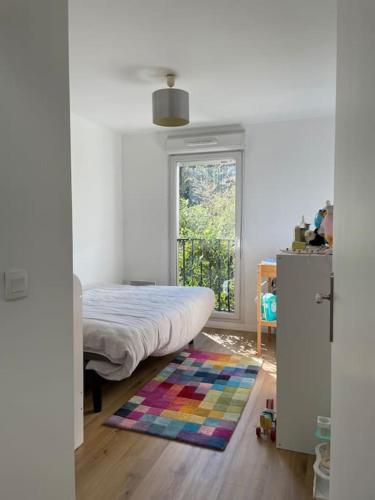 um quarto com uma cama, uma janela e um tapete em Maison proche ville olympique et stade de France em Saint-Denis