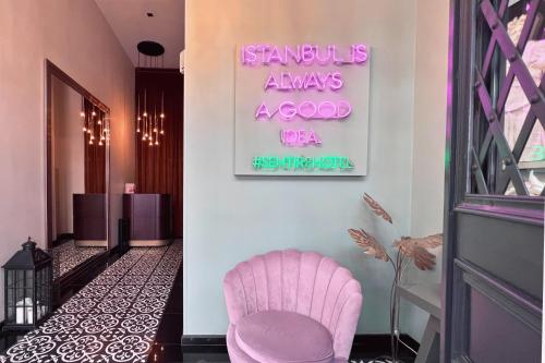 una sedia rosa in un corridoio con un cartello sul muro di Sentire Hotels & Residences a Istanbul