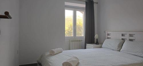 a white bedroom with a bed with a window at Casa Lima - AL in Valença