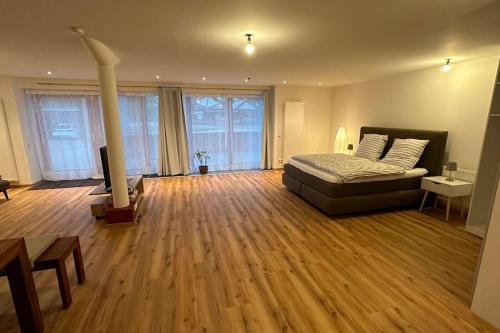a bedroom with a bed and wooden floors and windows at Loft Wohnung zwischen Altmühltal und Hallertau in Pförring