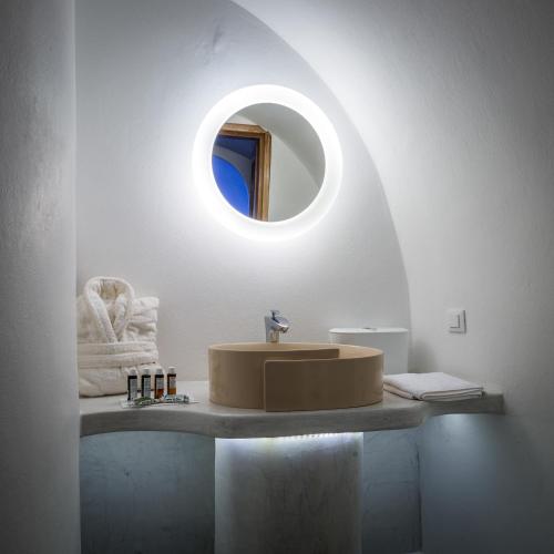 a bathroom with a sink and a round mirror at Elite Luxury Suites in Oia