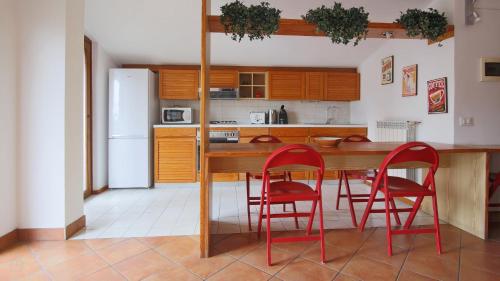 een keuken met een houten tafel en rode stoelen bij Italianway - Piazza Nuova 3 in San Fedele Intelvi
