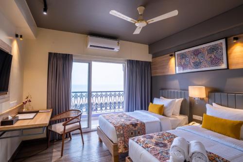 a hotel room with two beds and a balcony at Regenta Central Puri Odisha in Puri