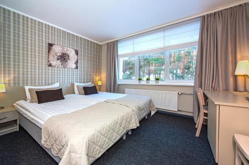 a hotel room with a bed and a window at Nykščio Namai & SPA in Anykščiai