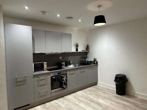 a kitchen with white cabinets and a stove top oven at Beautiful 1-Bed Apartment in Birmingham - Solihull in Birmingham