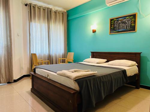 a bedroom with a bed with a blue wall at Ritz Gate Kalutara in Kalutara