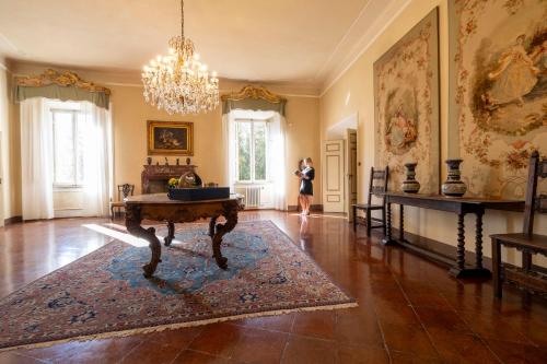 Eine Frau steht in einem Zimmer mit einem Tisch in einem Zimmer. in der Unterkunft Castello di Sovicille - Residenza d'Epoca in Sovicille