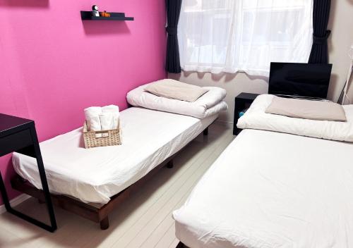two beds in a room with a pink wall at OHANA TOKYO HOUSE - Vacation STAY 71468v in Tokyo