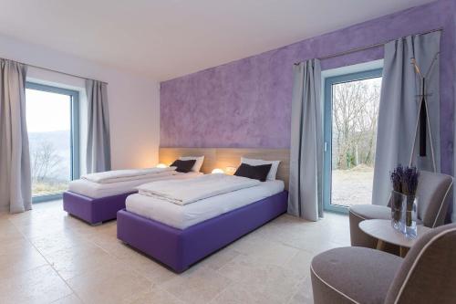2 Betten in einem Zimmer mit lila Wänden und Fenstern in der Unterkunft Villa Akazija in Buzet