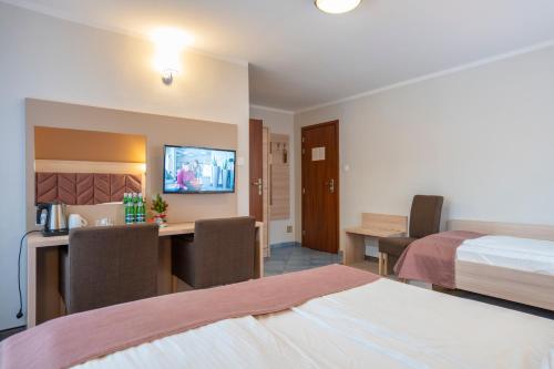 a hotel room with a bed and a desk with chairs at Pensjonat Carmen in Szklarska Poręba