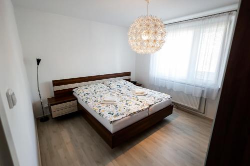 a bedroom with a bed and a chandelier at Coldweek apartment - Samorin near X-bionic sphere in Šamorín