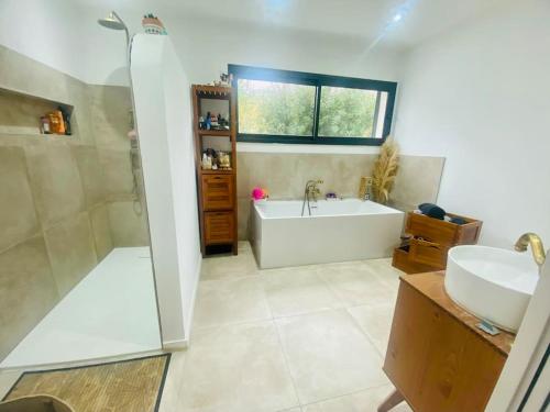 a bathroom with a tub and a sink and a shower at Villa charme et tradition in Poulx