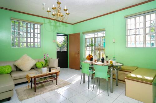 a living room with green walls and a table and chairs at Golden V Farms Hacienda in Malolos