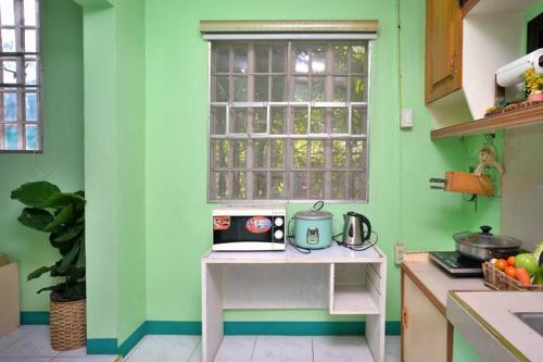 a kitchen with green walls and a table with a microwave at Golden V Farms Hacienda in Malolos
