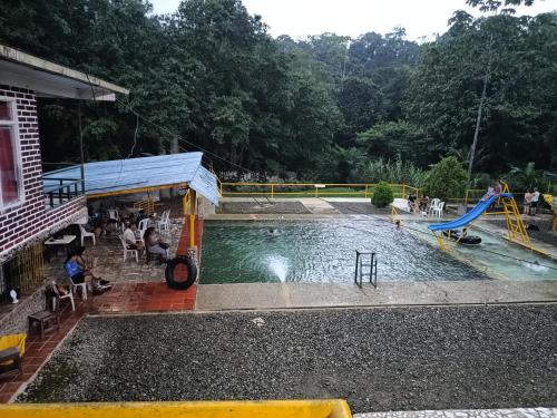a swimming pool with a slide and a playground at Hotel y restaurante Don Hato in Buenaventura