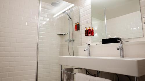 a white bathroom with a sink and a shower at Corsendonk Hooge Heyde in Lichtaart