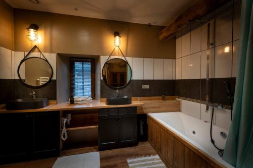 a bathroom with a tub and two sinks and a bath tub at Domaine de la Pommeraye & Spa in La Pommeraye