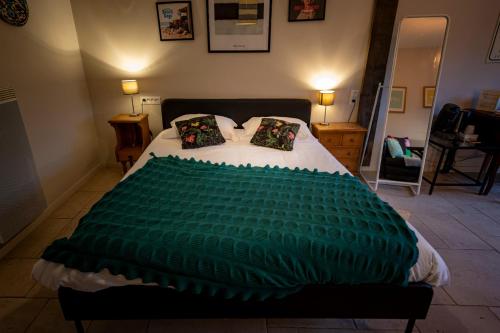 a bedroom with a bed with a green blanket on it at Domaine de la Pommeraye & Spa in La Pommeraye