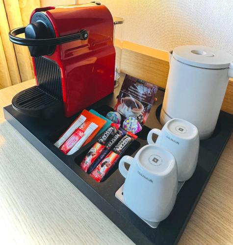 a counter top with a coffee maker and two cups at Best Western Plus Paris Orly Airport in Rungis