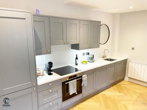 una cocina con armarios grises y encimeras blancas en Character filled Courtyard Escape en Harrogate