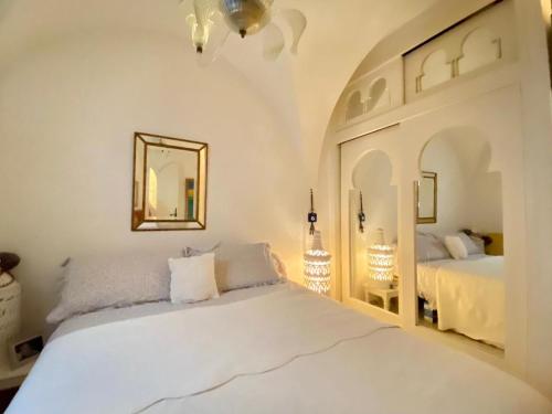 a white bedroom with two beds and a mirror at Dar Zahra - Sidi Bou Said in Douar el Hafey