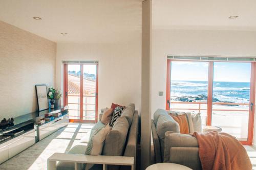 - un salon avec deux canapés et deux fenêtres dans l'établissement Just Like Home - Moledo Shoreline, à Moledo