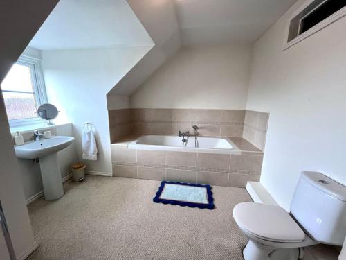 a bathroom with a tub and a toilet and a sink at Bright flat Chichester in Lavant