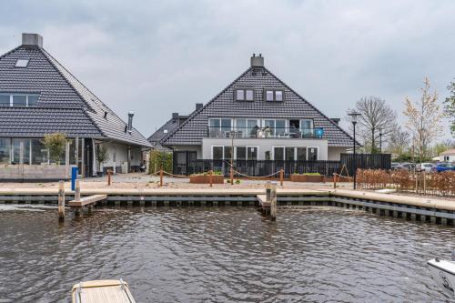 a large house with a dock next to a body of water at Welcome in - Appartement - Paviljoenwei 4 - Sneek 'Havenzicht' in Offingawier