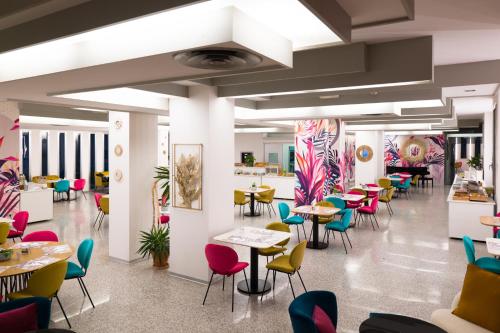 a dining room with tables and colorful chairs at Hotel Bellevue in Rimini