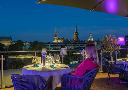 a woman sitting at a table with a view of the city at Residenz am Zwinger in Dresden
