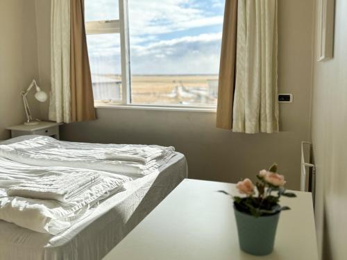 a bedroom with a bed and a vase of flowers on a table at Hotel Drangshlid in Skogar