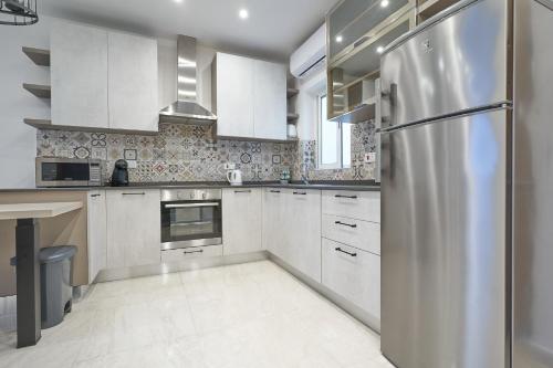 a kitchen with white cabinets and a stainless steel refrigerator at Comfort Lounge Loft - W/1BR in Sliema
